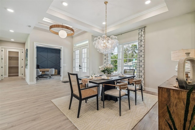 dining space featuring baseboards, french doors, light wood finished floors, a raised ceiling, and crown molding