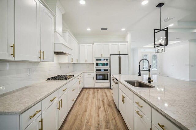 kitchen with stainless steel gas stovetop, white cabinetry, a sink, and double wall oven