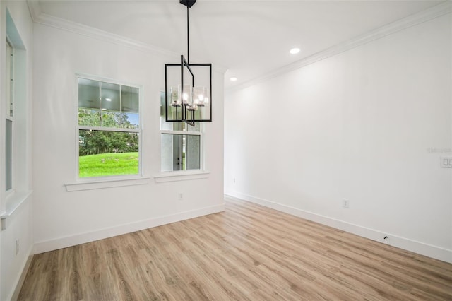 unfurnished dining area with light wood finished floors, baseboards, crown molding, and an inviting chandelier