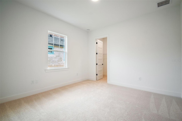 empty room with baseboards, visible vents, and light colored carpet