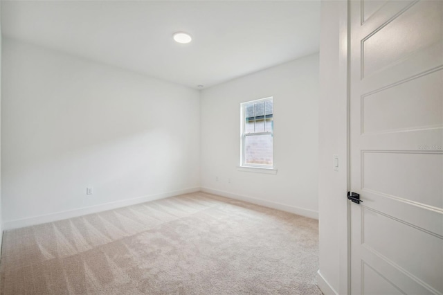 spare room with light carpet and baseboards