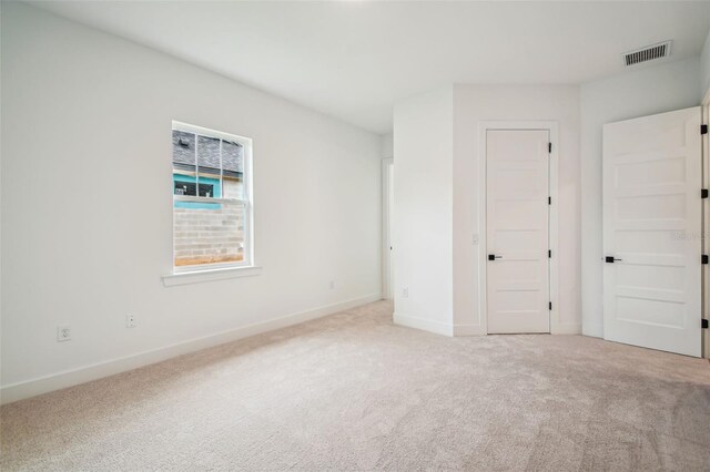 unfurnished bedroom with light carpet, visible vents, and baseboards