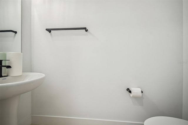 bathroom featuring a sink, toilet, and baseboards