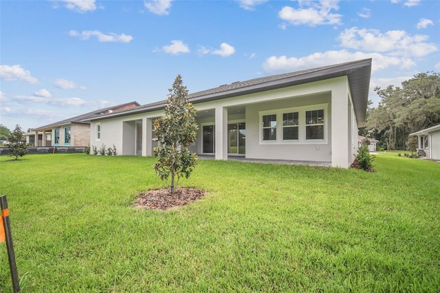 rear view of house with a lawn and stucco siding