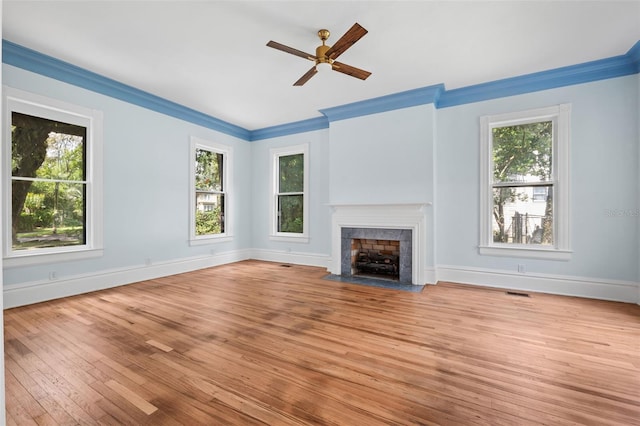 unfurnished living room with a healthy amount of sunlight, crown molding, and light hardwood / wood-style flooring