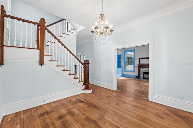 foyer with an inviting chandelier, crown molding, and hardwood / wood-style floors