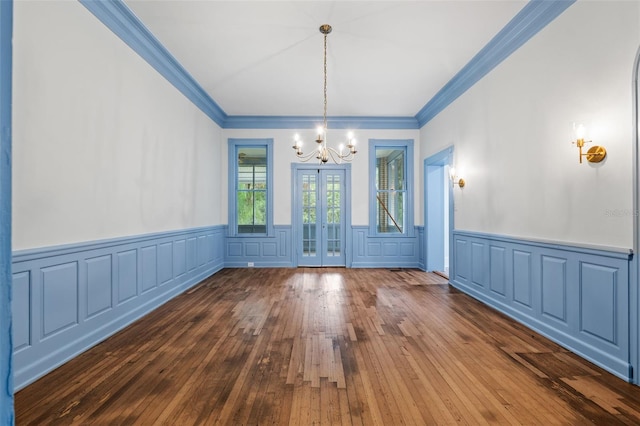 unfurnished dining area featuring ornamental molding, a notable chandelier, and hardwood / wood-style floors