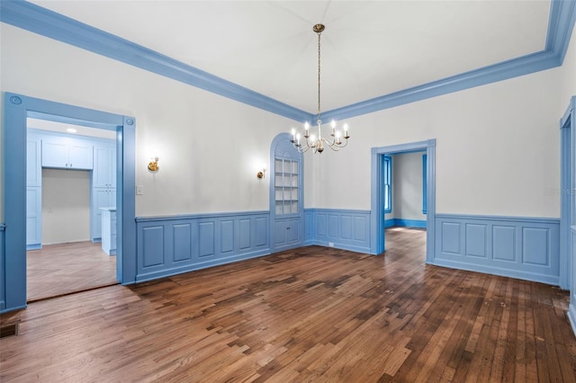 unfurnished dining area with ornamental molding, an inviting chandelier, and dark hardwood / wood-style flooring