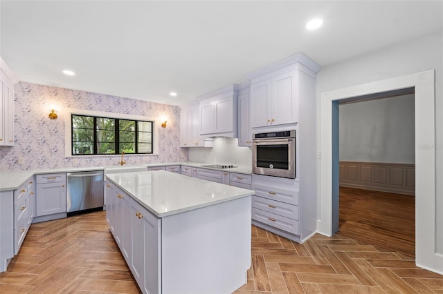 kitchen featuring white cabinets, appliances with stainless steel finishes, light parquet flooring, and a kitchen island