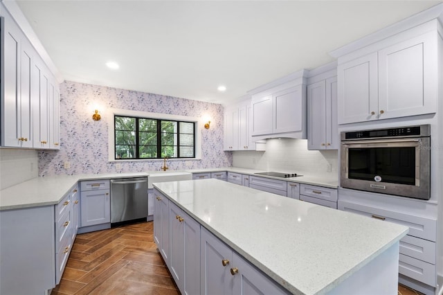 kitchen featuring light stone counters, sink, a kitchen island, stainless steel appliances, and parquet flooring