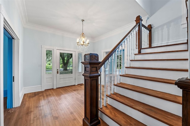 entryway with an inviting chandelier, crown molding, and hardwood / wood-style floors