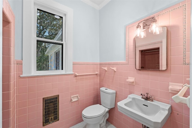 bathroom with heating unit, tile walls, sink, and toilet