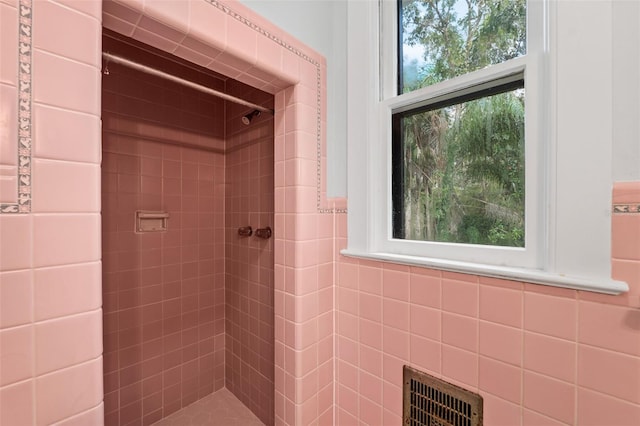 bathroom featuring a tile shower and tile walls