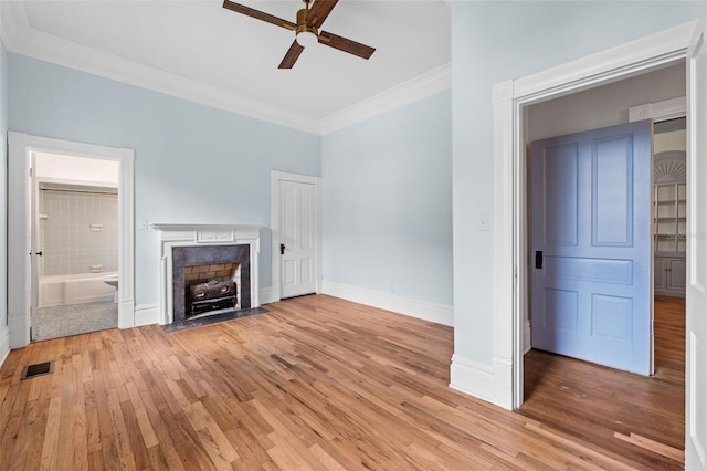 unfurnished living room featuring a fireplace, ornamental molding, ceiling fan, and light hardwood / wood-style flooring