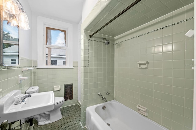 full bathroom with tiled shower / bath combo, tile walls, toilet, and heating unit