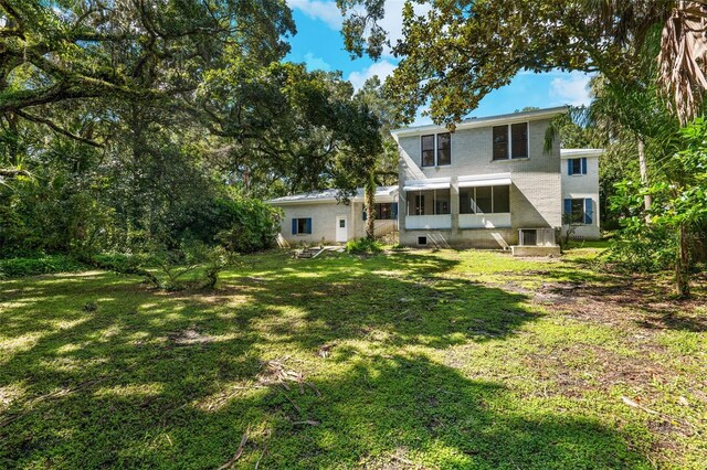 back of property with a sunroom and a yard