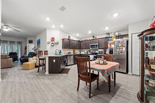 dining room with light wood-type flooring, lofted ceiling, sink, and ceiling fan