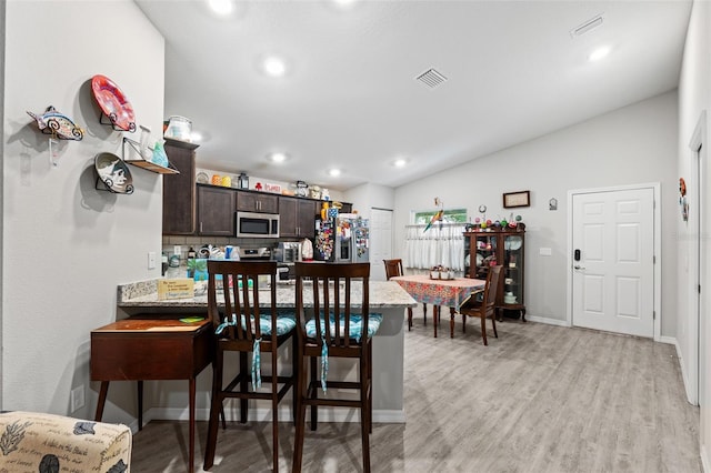 dining space with light wood-type flooring and lofted ceiling