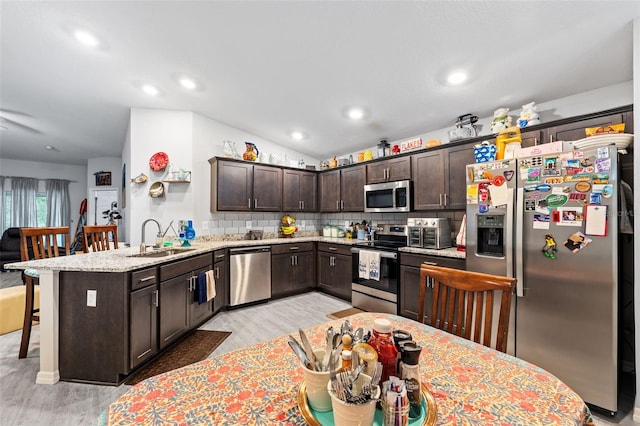 kitchen with dark brown cabinetry, lofted ceiling, sink, appliances with stainless steel finishes, and light wood-type flooring