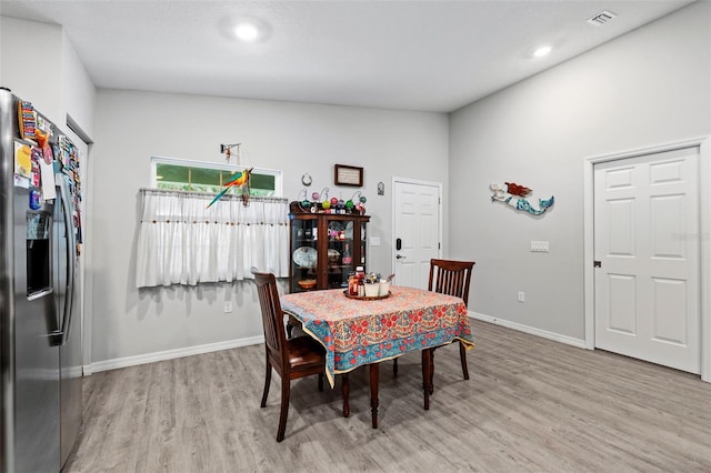 dining room featuring light hardwood / wood-style floors and high vaulted ceiling