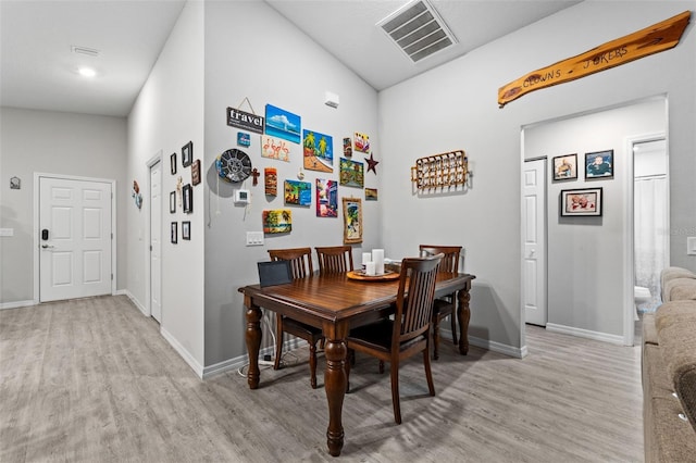 dining room featuring light wood-type flooring and lofted ceiling