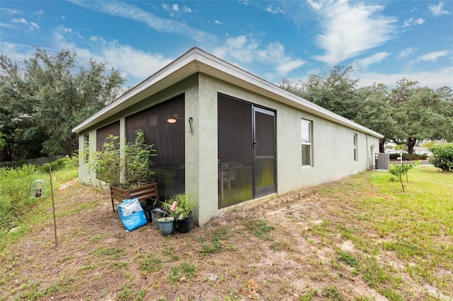 view of side of property featuring central AC unit and a lawn