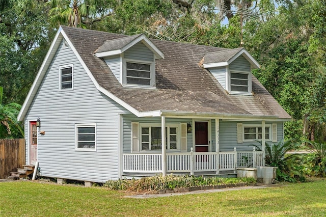 new england style home featuring covered porch and a front lawn