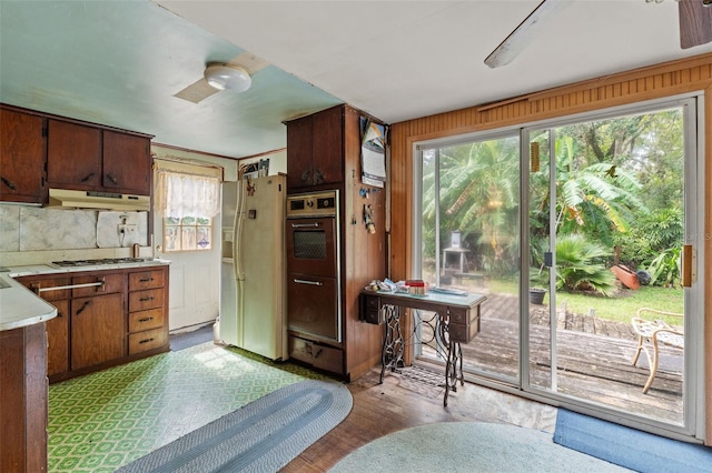 kitchen with stainless steel gas cooktop, white fridge with ice dispenser, and light wood-type flooring