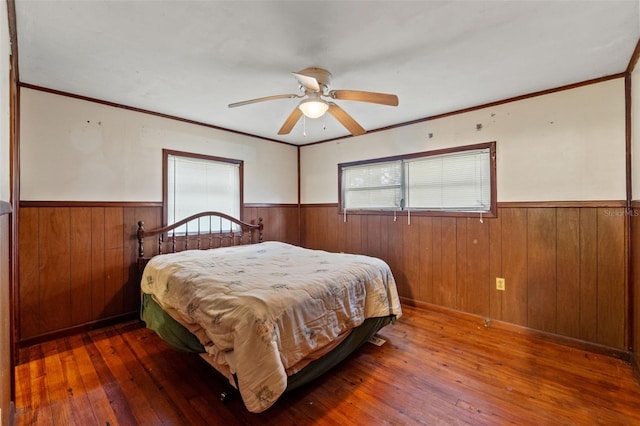 bedroom featuring wood walls, crown molding, ceiling fan, and dark hardwood / wood-style flooring