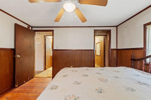 bedroom with light hardwood / wood-style flooring, wood walls, crown molding, and ceiling fan