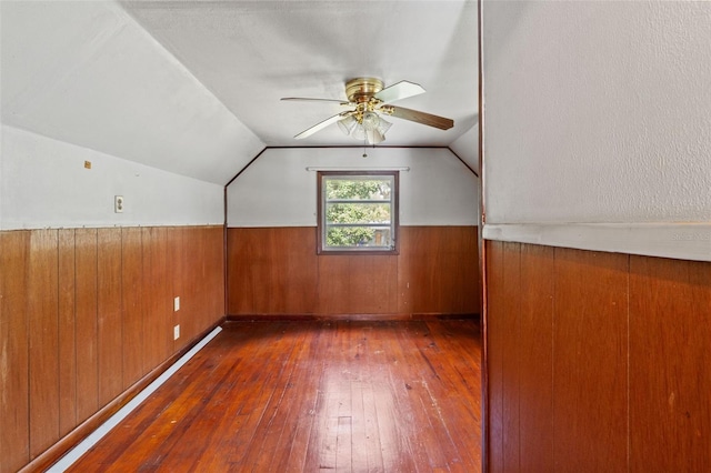 bonus room featuring wooden walls, vaulted ceiling, dark hardwood / wood-style floors, and ceiling fan