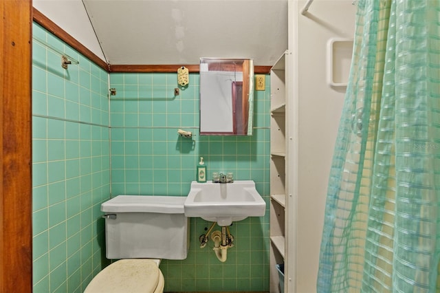 bathroom featuring tile walls, sink, curtained shower, and toilet