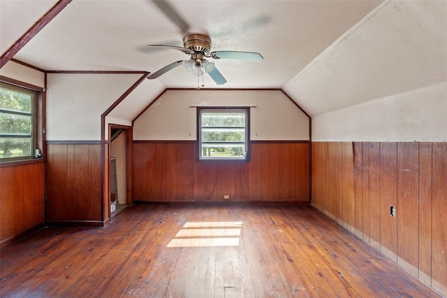 additional living space featuring lofted ceiling, wooden walls, dark hardwood / wood-style floors, and ceiling fan