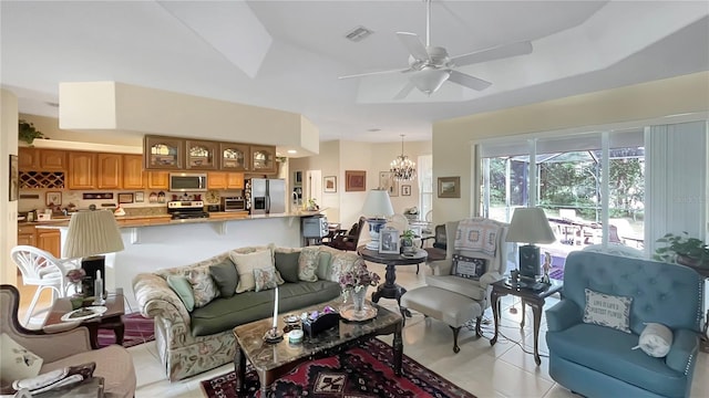 tiled living room with ceiling fan with notable chandelier