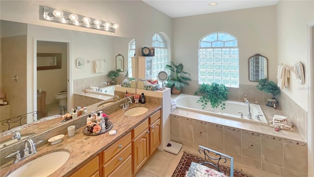 bathroom featuring vanity, tiled bath, tile patterned flooring, and toilet