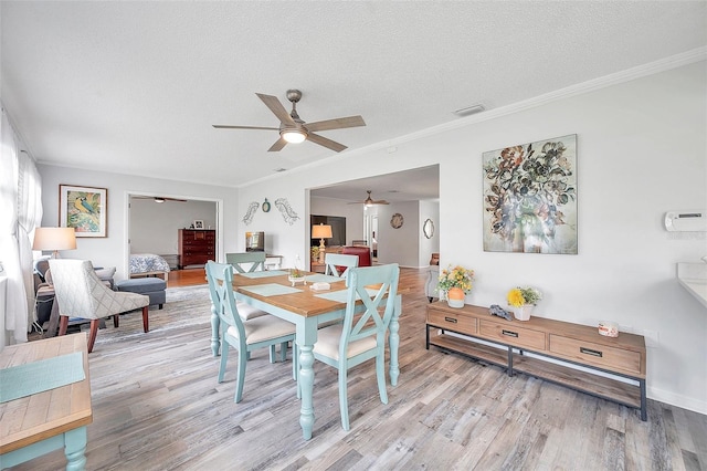 dining area with ornamental molding, ceiling fan, light hardwood / wood-style floors, and a textured ceiling