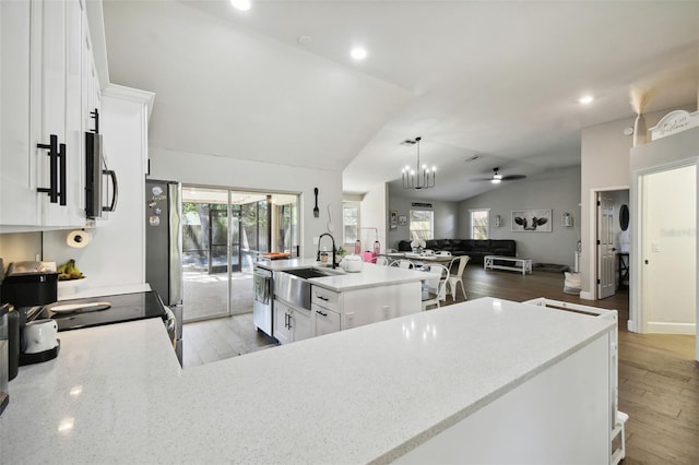 kitchen featuring a kitchen island with sink, vaulted ceiling, light hardwood / wood-style floors, and white cabinets