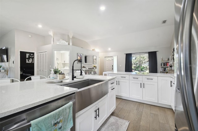 kitchen with stainless steel fridge, light wood-type flooring, light stone counters, and white cabinets