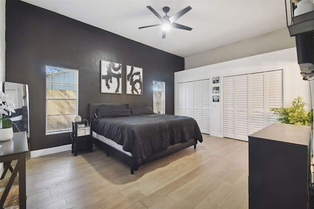 bedroom featuring ceiling fan, multiple closets, and light hardwood / wood-style flooring