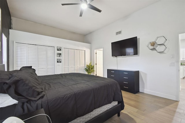 bedroom featuring two closets, light hardwood / wood-style floors, and ceiling fan