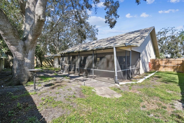 rear view of property featuring a sunroom and a yard