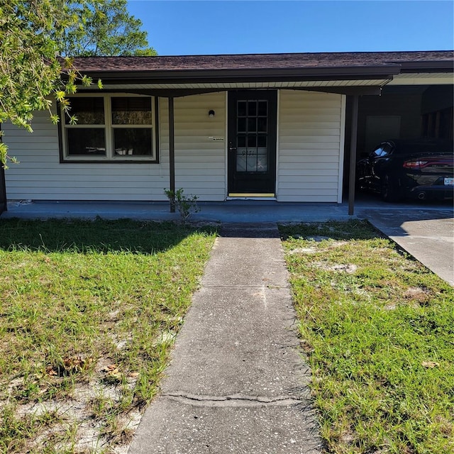 entrance to property featuring a yard, a porch, and a garage