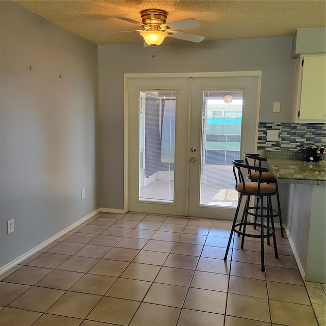 entryway featuring french doors, a textured ceiling, light tile patterned floors, and ceiling fan