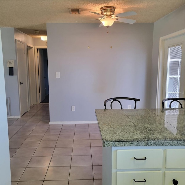 kitchen with light tile patterned flooring, ceiling fan, and a textured ceiling