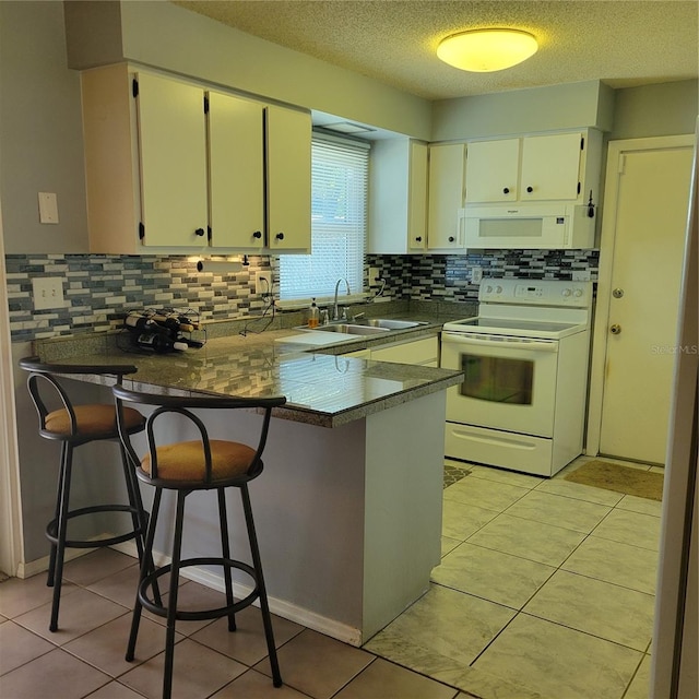 kitchen featuring white appliances, sink, kitchen peninsula, backsplash, and a textured ceiling