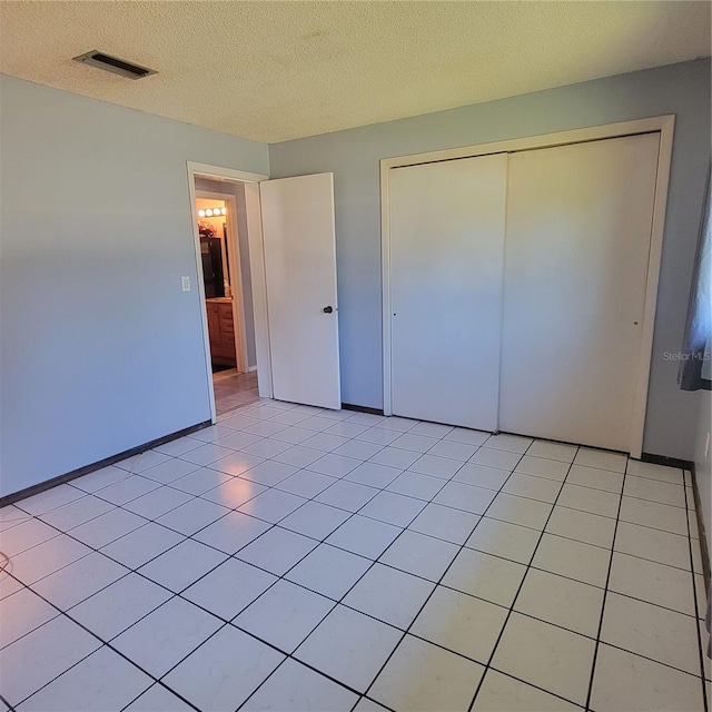 unfurnished bedroom with a textured ceiling, a closet, and light tile patterned floors