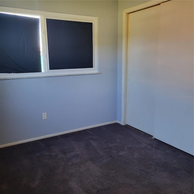 spare room with dark colored carpet