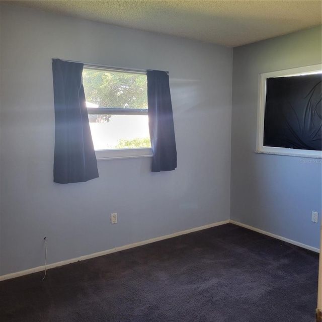 carpeted empty room featuring a textured ceiling