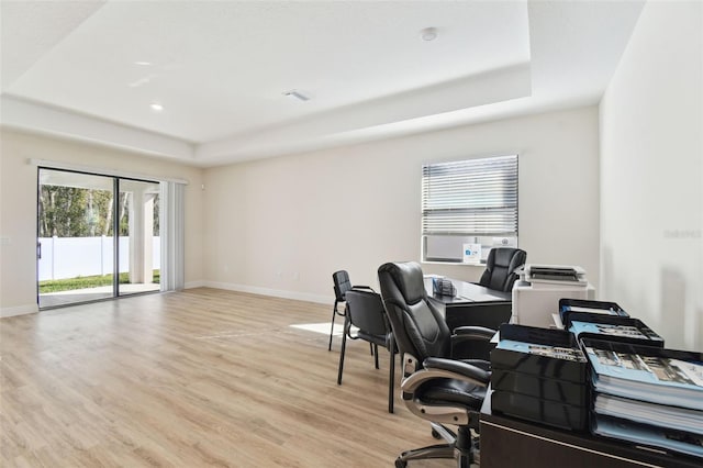 office featuring a tray ceiling and light wood-type flooring