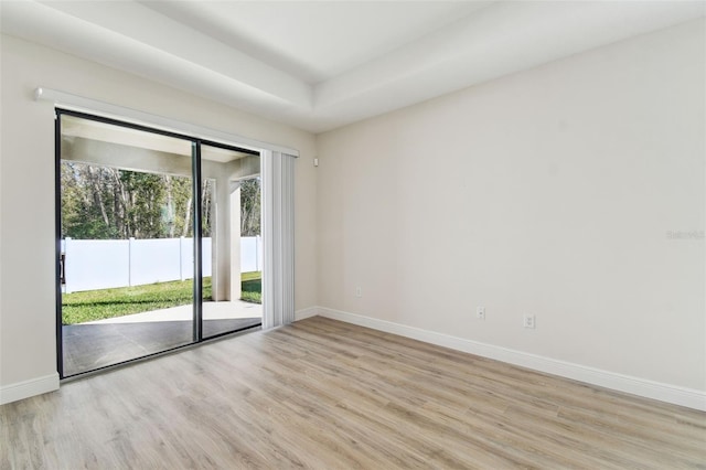 unfurnished room with a tray ceiling and light hardwood / wood-style flooring